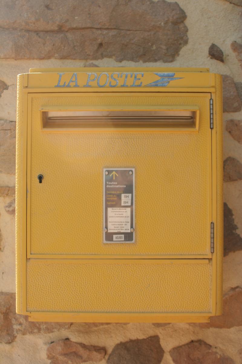 Boîte aux lettres jaune de La Poste, fixée au mur en pierre de la mairie de Vendranges, avec les horaires de levée.