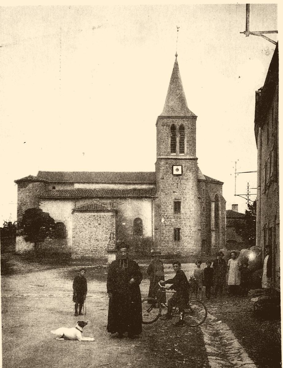 Photographie ancienne teintée sépia : l'église Saint-Genest de Vendranges et son clocher, avec un curé, des enfants, un cycliste et un chien sur la place, vers 1915.