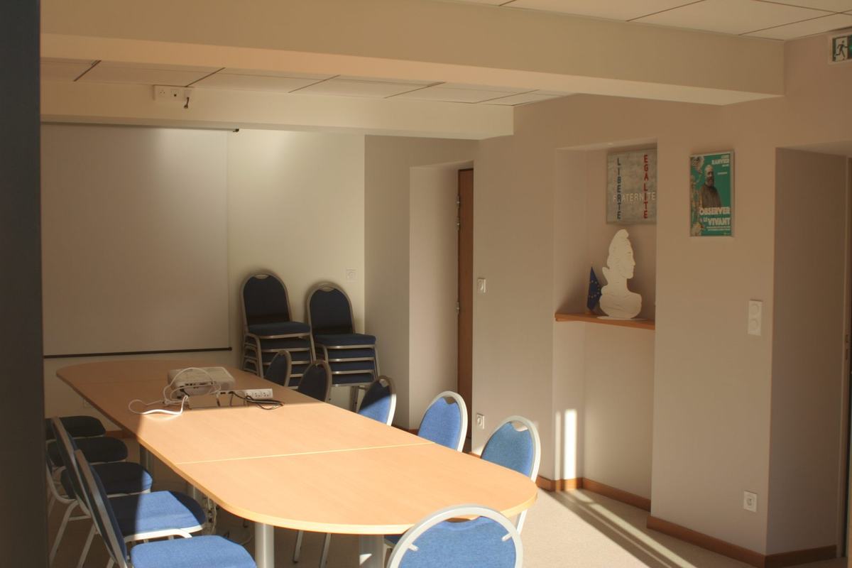 Intérieur de la salle Louis-Ranvier à la mairie de Vendranges : table de réunion ovale, chaises bleues, vidéoprojecteur, et dans une niche un buste de Marianne avec une affiche consacrée à Louis Ranvier.