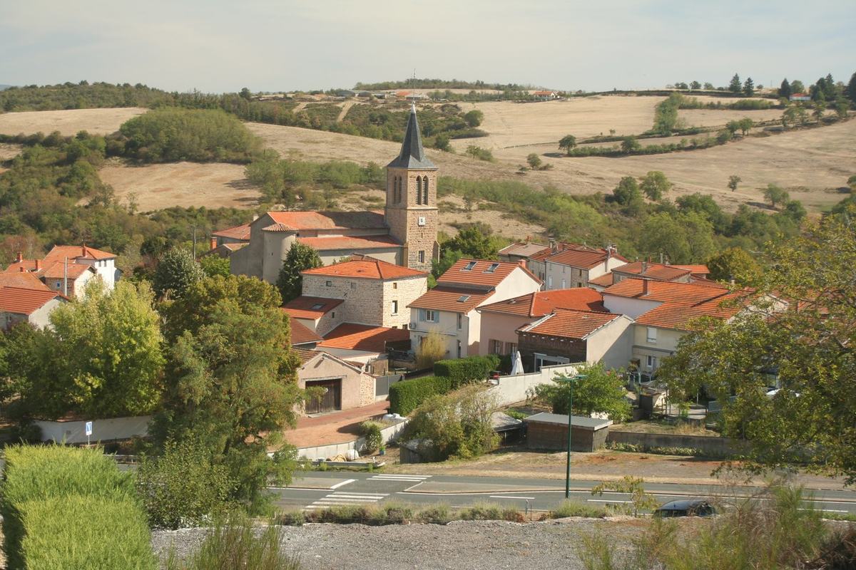 Vue d'ensemble du bourg de Vendranges avec le clocher de l'église Saint-Genest, entouré de champs et de collines.